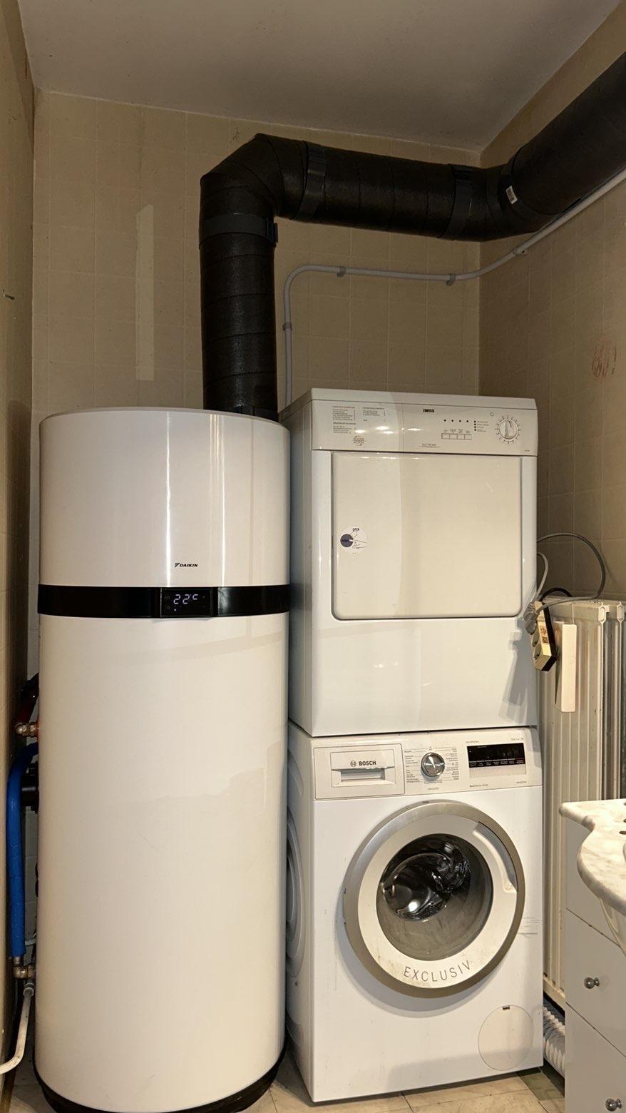 un ballon d'eau chaude thermodynamique blanc à côté d'une colonne de lavage